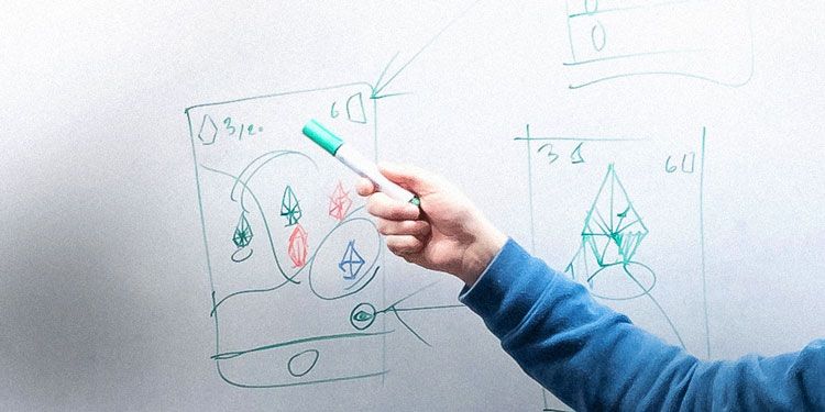 Närbild på hand som pekar med en penna på en skiss på whiteboard